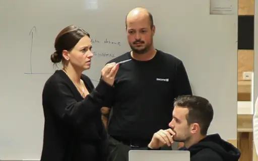 Teambuilding-Workshop bei become.1: Drei Kollegen diskutieren engagiert Strategien vor einem Whiteboard