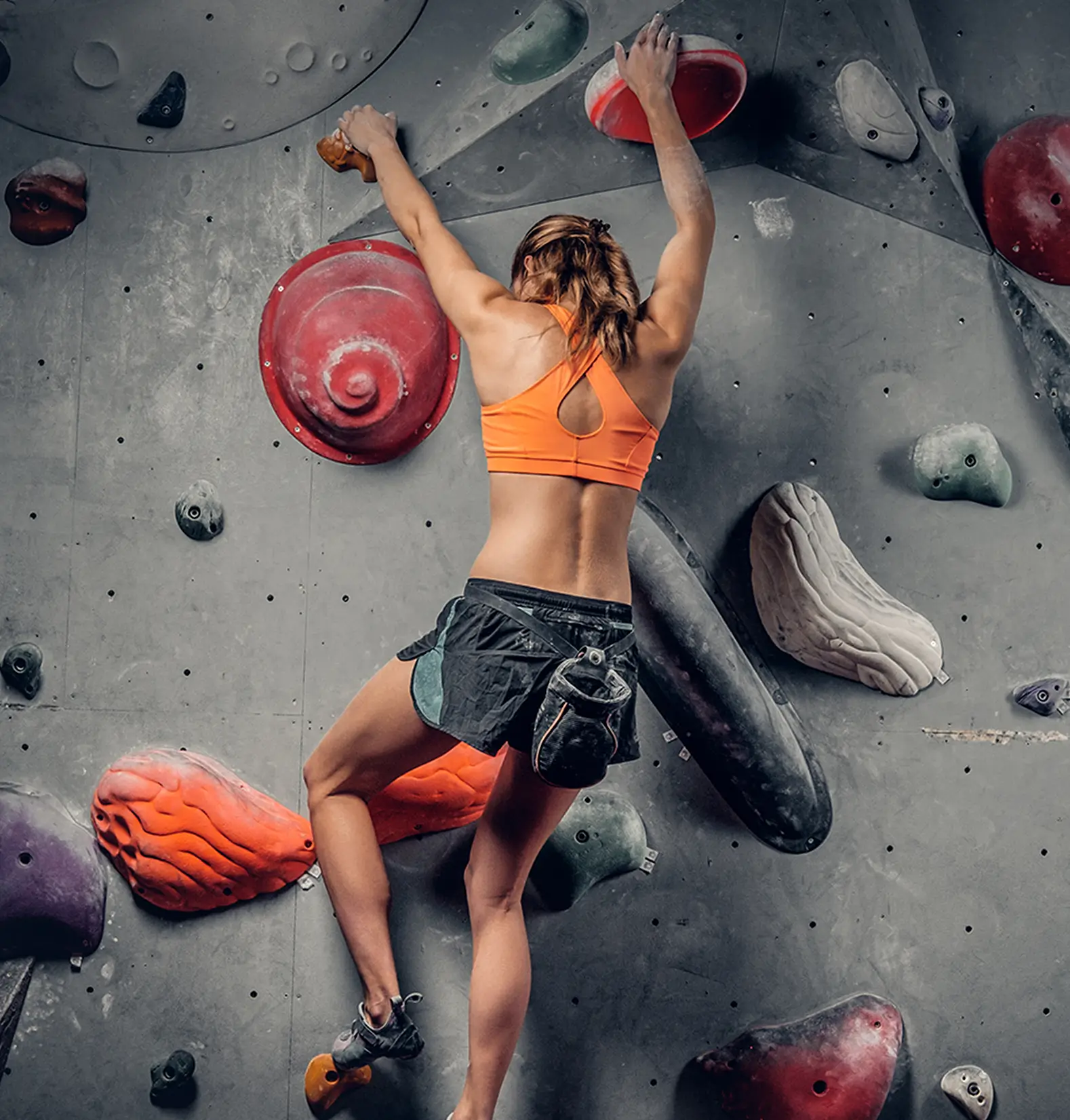 Frau erklimmt eine Kletterwand in einer Halle