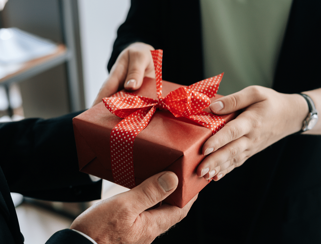 Eine Person überreicht einer anderen ein Geschenk mit roter Schleife