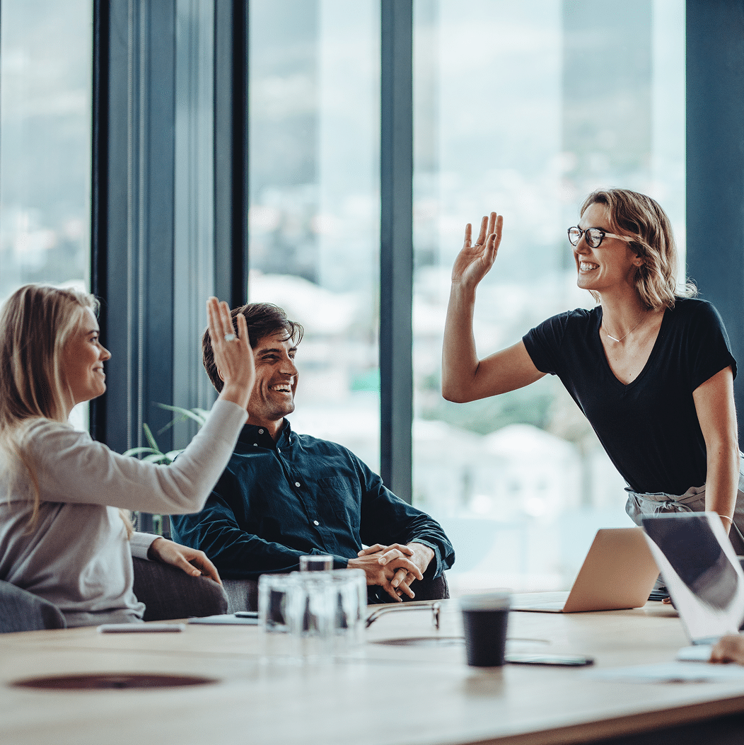 Drei Kollegen im Büro lachen und geben sich gegenseitig ein High-Five
