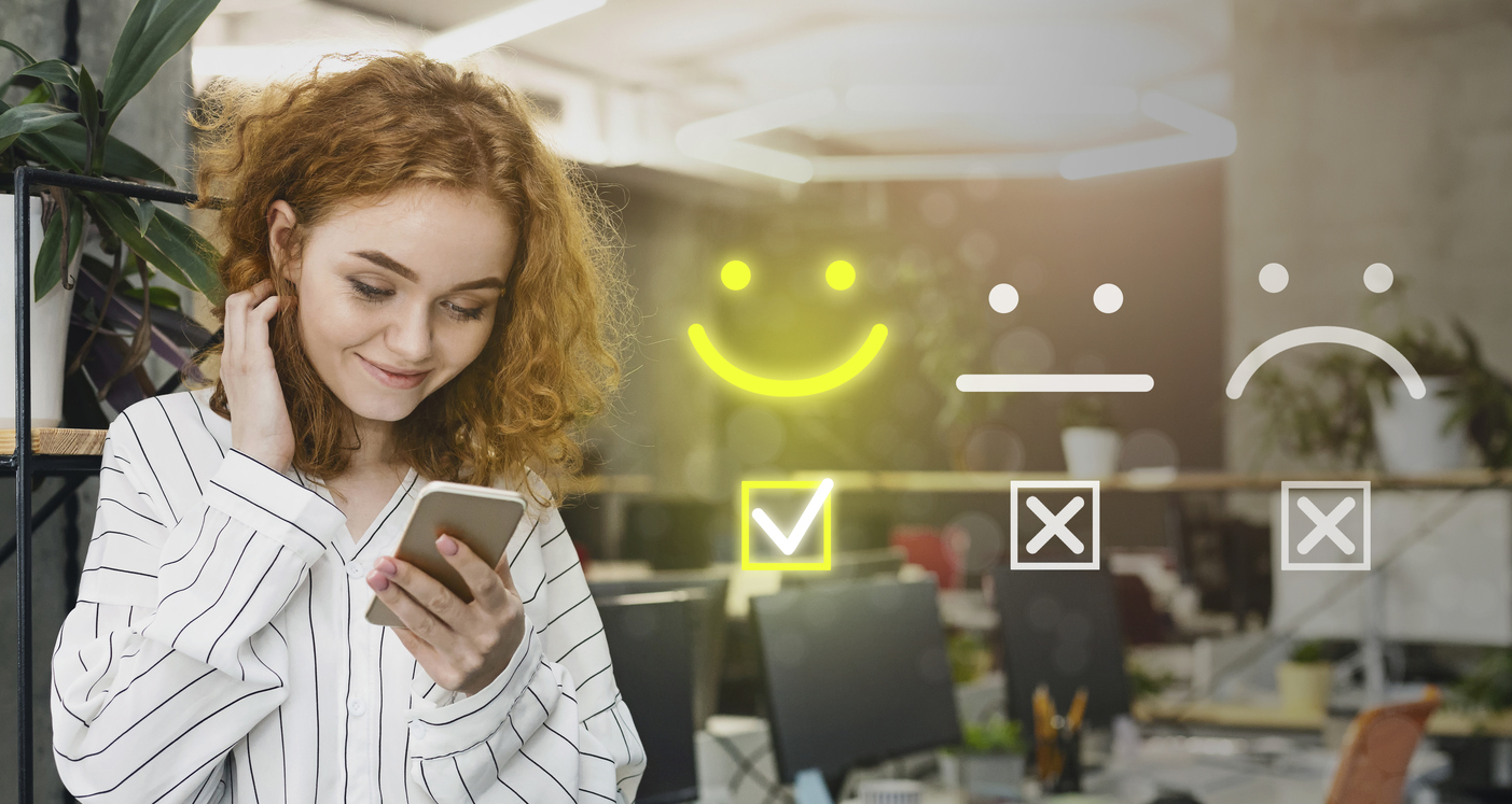Junge Mitarbeiterin lächelt, während sie positives Feedback auf dem Smartphone abgibt – Illustration der hohen Mitarbeiterzufriedenheit mit become.1 Benefits