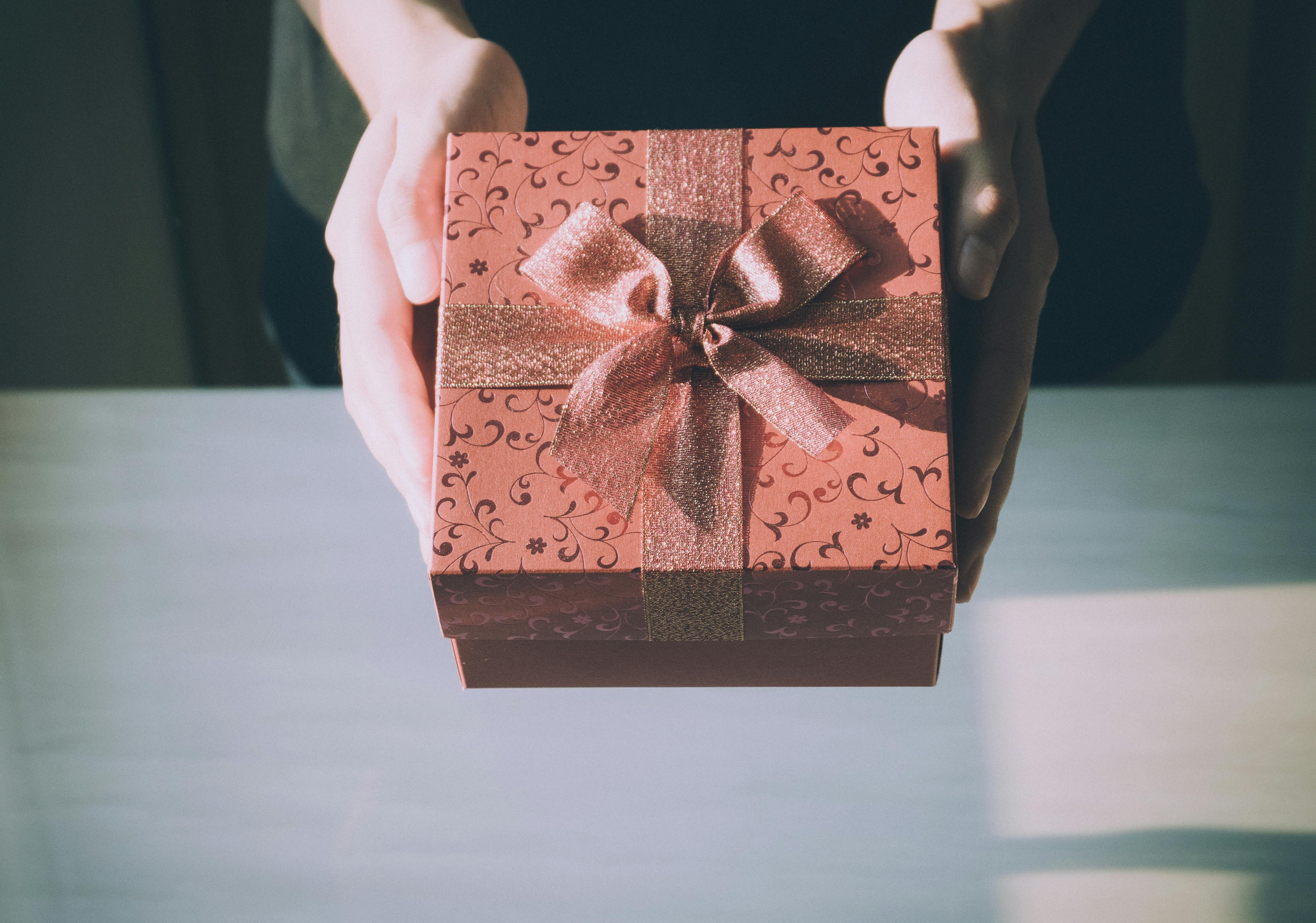 Hände überreichen ein schön verpacktes Geschenk – Symbol für steuerfreie Mitarbeitergeschenke und Wertschätzung über die become.1 Plattform