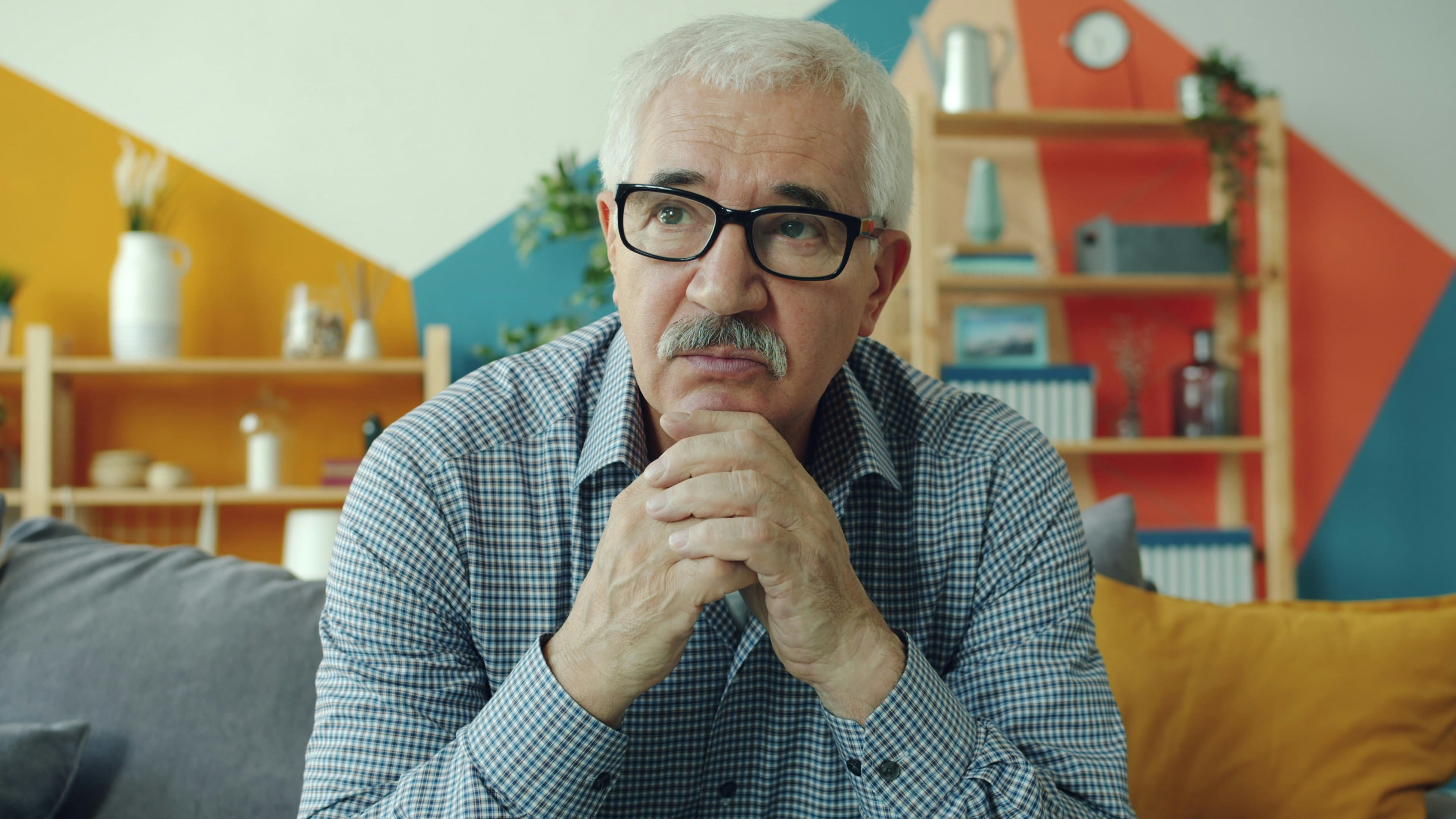 Älterer Mann mit Brille, Kinn auf die Hände gestützt