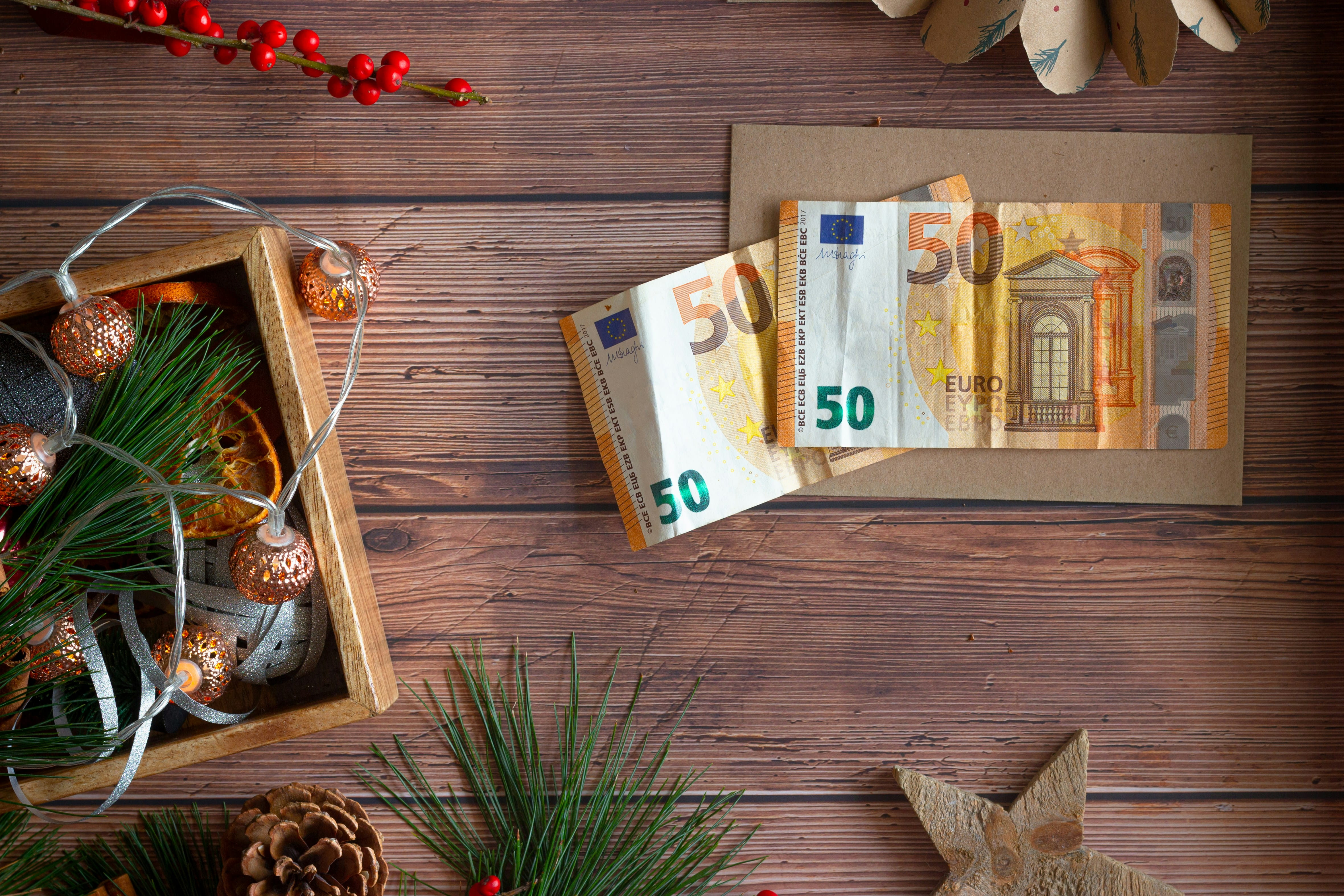 50 Euro Scheine liegen auf einem Umschlag mit Weihnachtsdeko drumherum